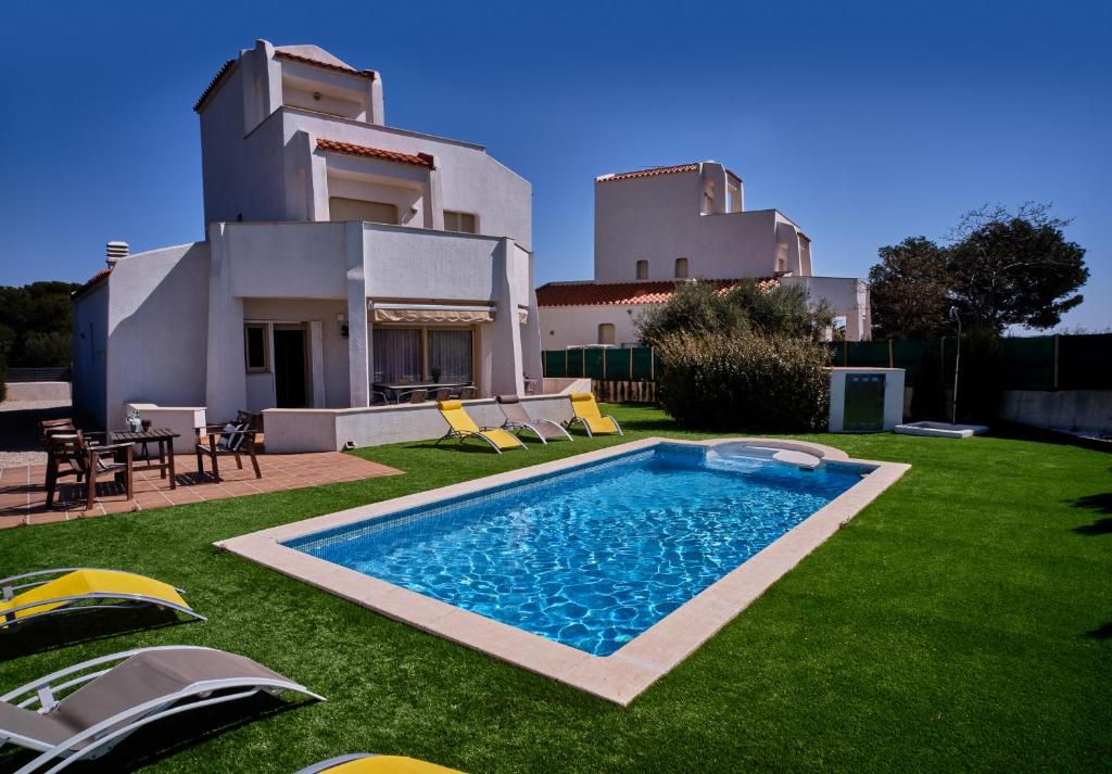 a villa with a swimming pool in front of a house at Villa Almadrava in Tarragona