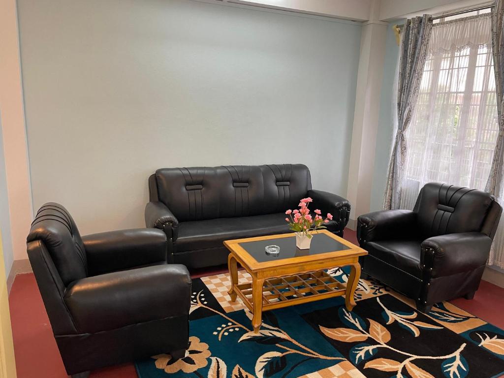 a living room with black leather furniture and a coffee table at Keeon Private Room Top in Shillong