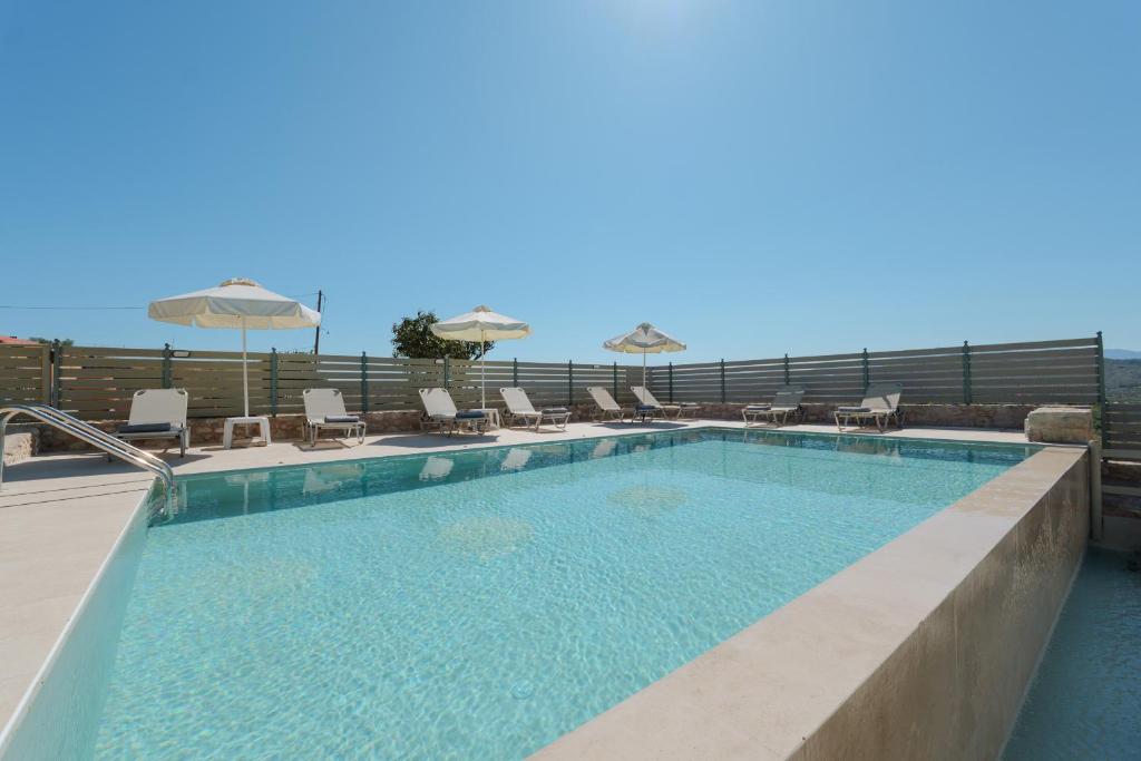 uma piscina com cadeiras e guarda-sóis num edifício em Villa Amarantos - Private pool em Stamnoí