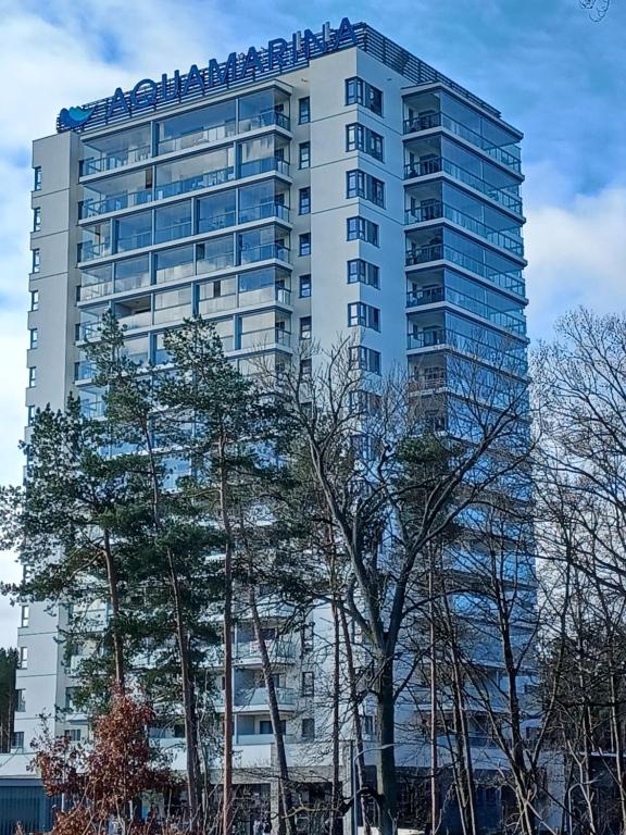 un edificio alto con árboles delante de él en Aquamarina ONYX 13 en Międzyzdroje