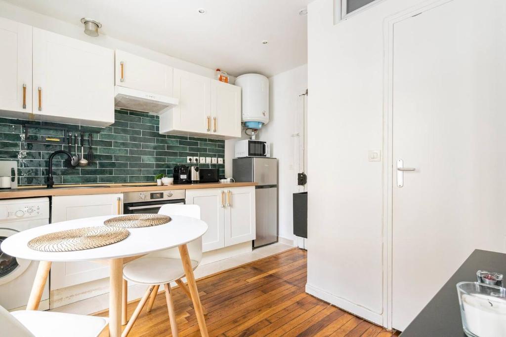 une cuisine avec des armoires blanches et une table et des chaises dans l'établissement Cocoon in the heart of Batignolles | By Airnest, à Paris