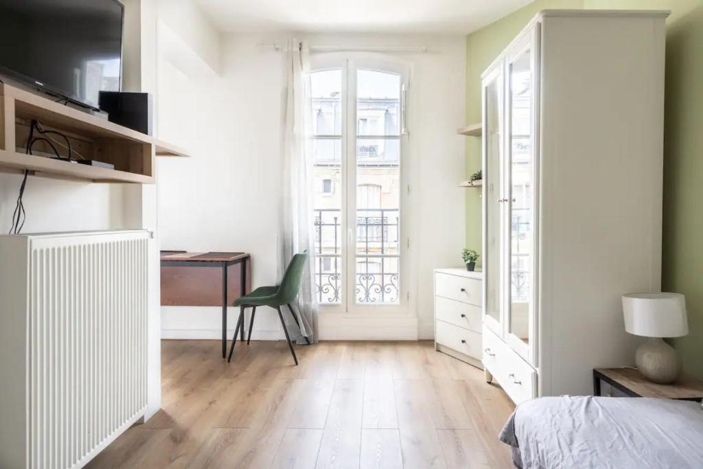 een slaapkamer met een bed, een bureau en een raam bij Cocon aux portes de Paris in Clichy