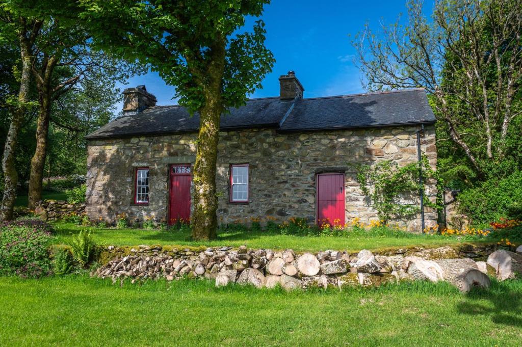 an old stone house with a red door at Mountain Cottage in Llanaelhaiarn