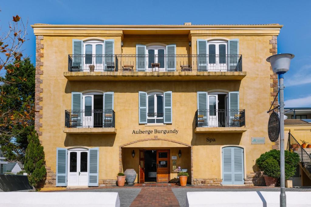 an orange building with blue windows and balconies at Auberge Burgundy Boutique Hotel & Spa in Hermanus