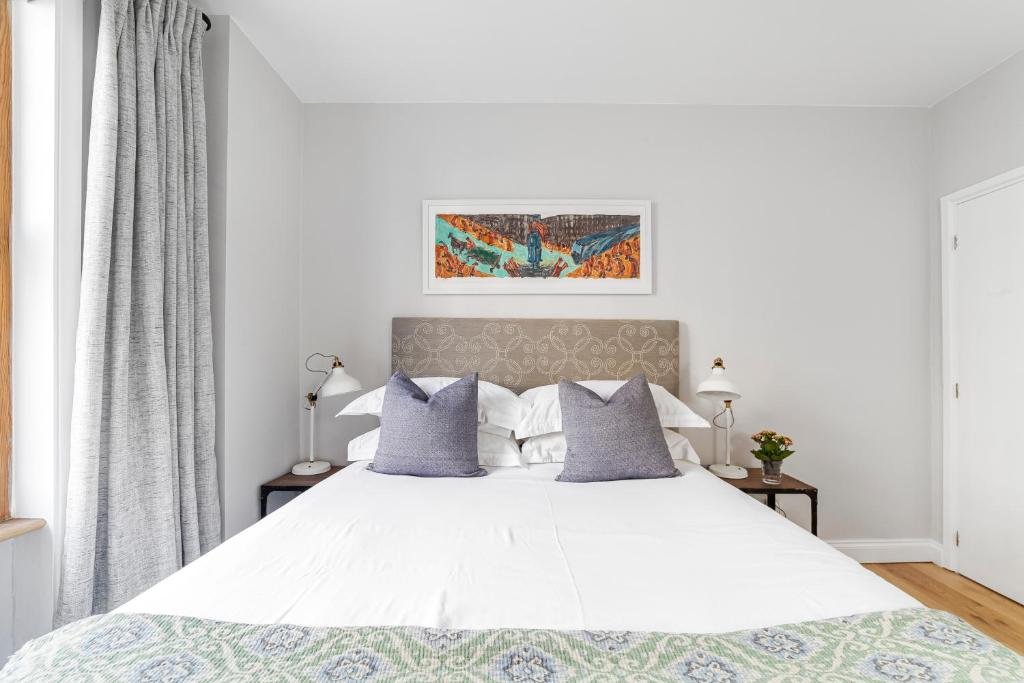 a bedroom with a large white bed with gray pillows at Munster Village in Fulham in London
