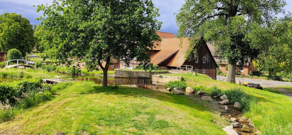 a house with a river in front of a building at Bruchmühlen in Bruchhausen-Vilsen