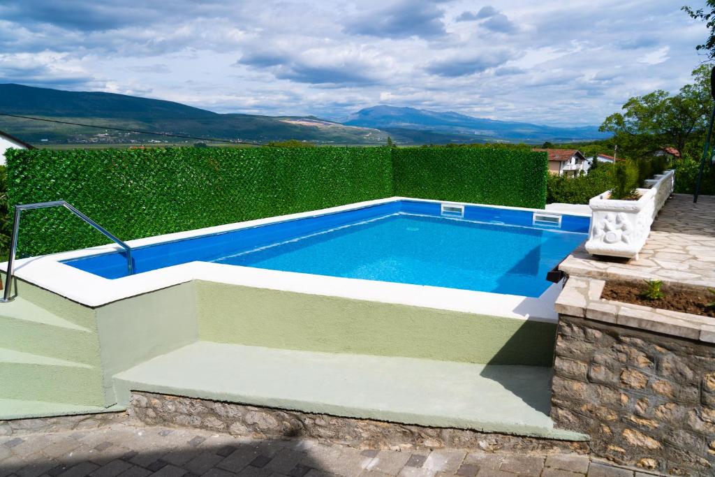 a swimming pool in a garden with a hedge at Holiday Home IFI in Mostar