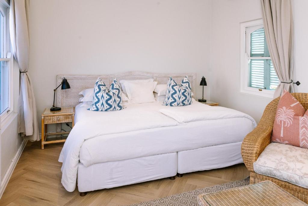 a bedroom with a white bed with blue and white pillows at Auberge Burgundy Boutique Hotel & Spa in Hermanus