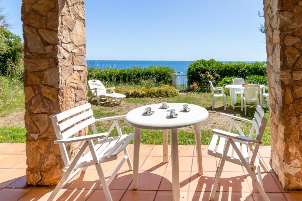 una mesa blanca y sillas en un patio con vistas al océano en Carboneras 48 Apartamento en primera línea de mar, en Girona