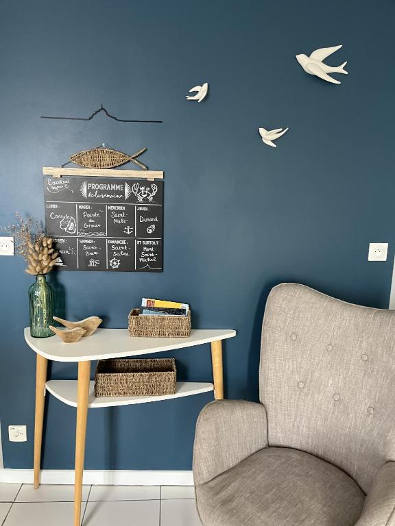 une pièce bleue avec une chaise, une table et un tableau noir dans l'établissement L Entre-Deux-Gîtes à Saint-Marcan-Baie du Mont-Saint-Michel, à Saint-Marcan