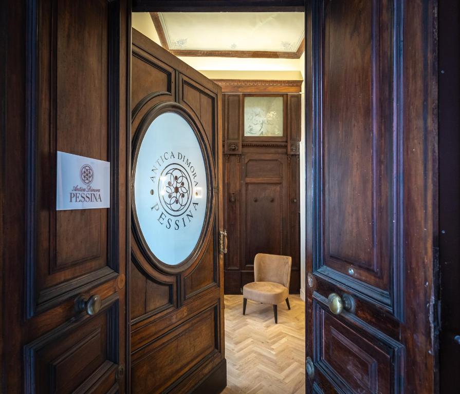 Partially open wooden doors with frosted glass and Antica Dimora Pessina logo, revealing a beige chair inside