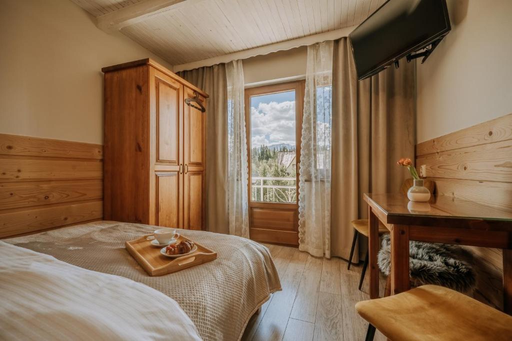1 dormitorio con cama, escritorio y ventana en GOŚCINA u MARYNY Sauna & Balia en Poronin