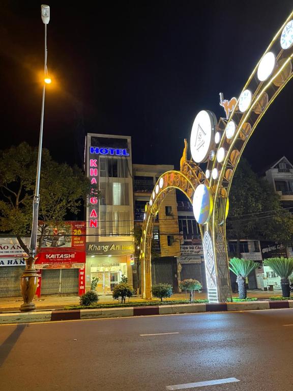 una strada di città di notte con un edificio con orologio di Khách sạn Khang An Buôn Ma Thuột a Buôn Ma Thuột