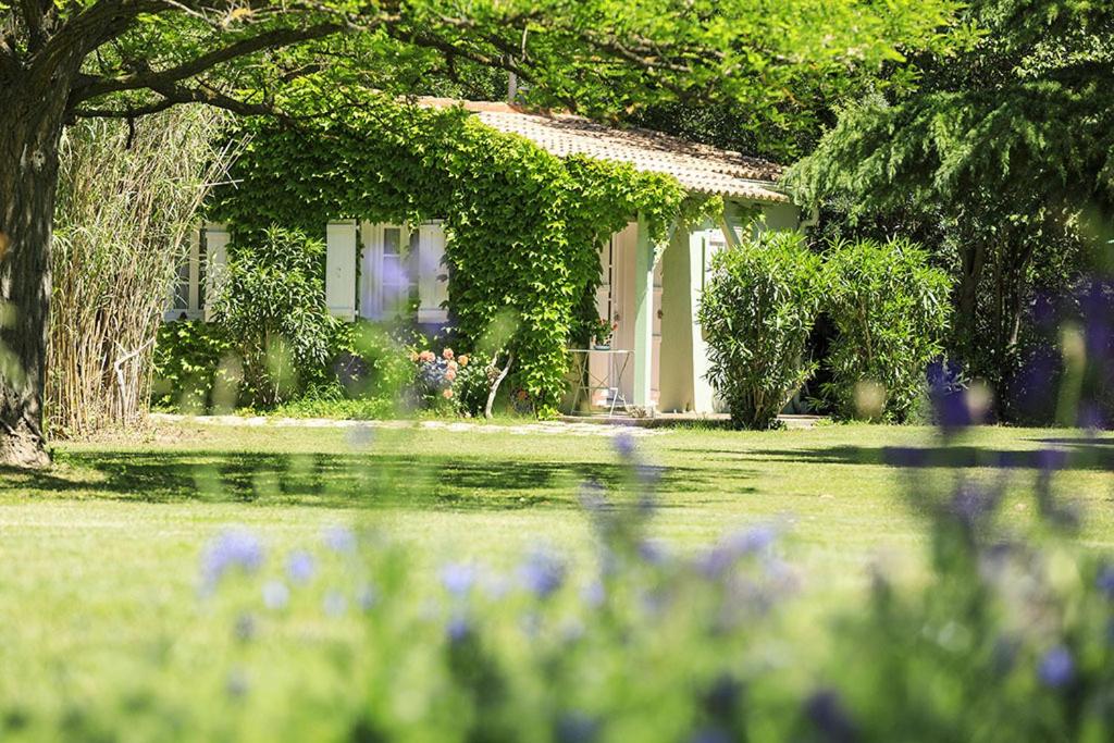 ein Haus in einem Garten mit Blumen im Vordergrund in der Unterkunft Les Gîtes du Domaine de Rhodes in Avignon