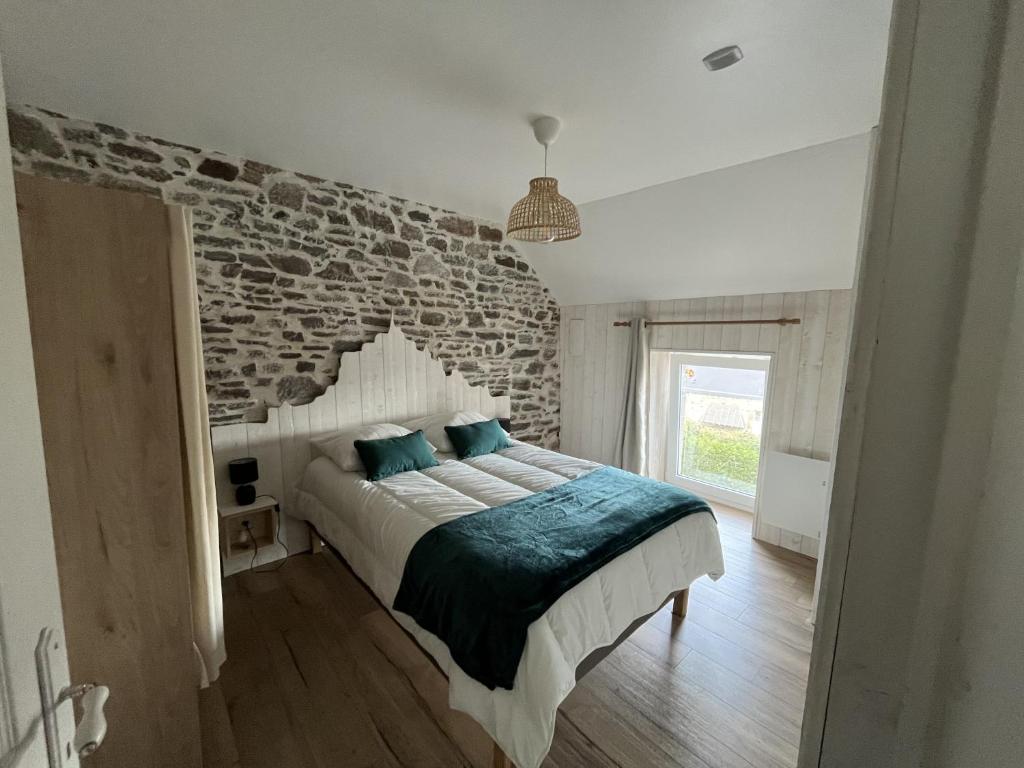 a bedroom with a bed with a stone wall at L Entre-Deux-Gîtes à Saint-Marcan-Baie du Mont-Saint-Michel in Saint-Marcan