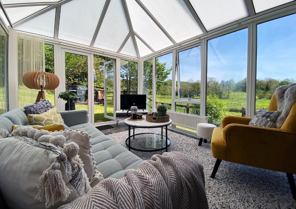una sala de estar con un salón acristalado con ventanas de cristal. en Granary Cottage St Clears, en St Clears