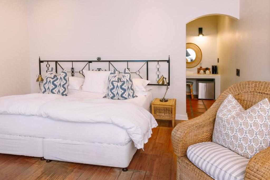 a bedroom with a white bed with blue and white pillows at Auberge Burgundy Boutique Hotel & Spa in Hermanus