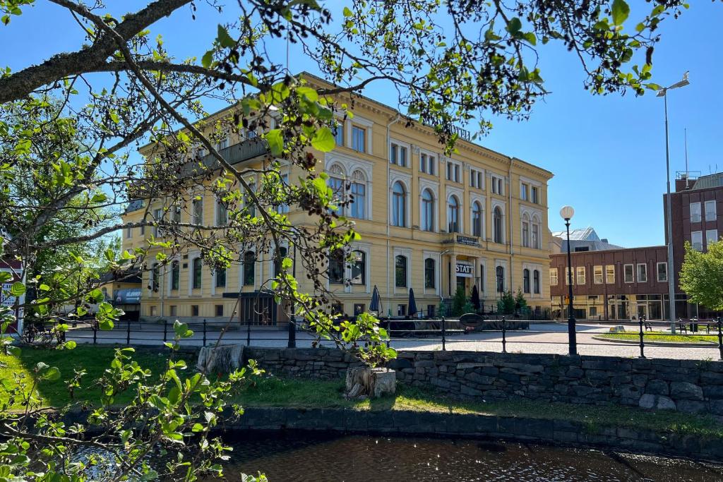 un grand bâtiment jaune en face d'une rue dans l'établissement Stadshotellet Kristinehamn, à Kristinehamn