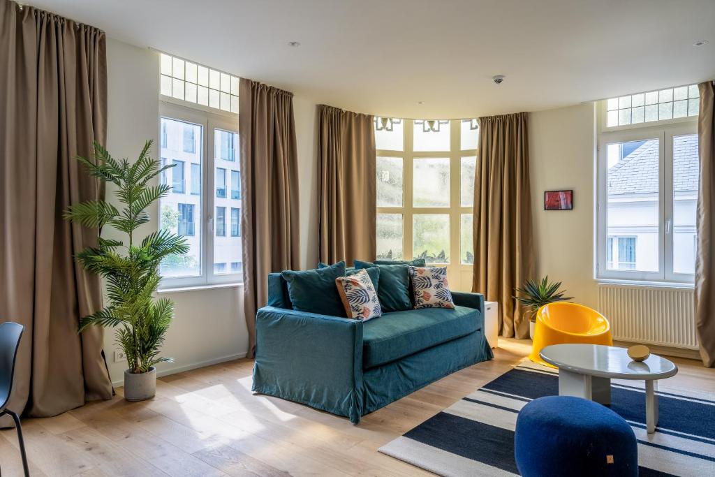 a living room with a blue couch and windows at Smartflats - Meir Antwerp in Antwerp