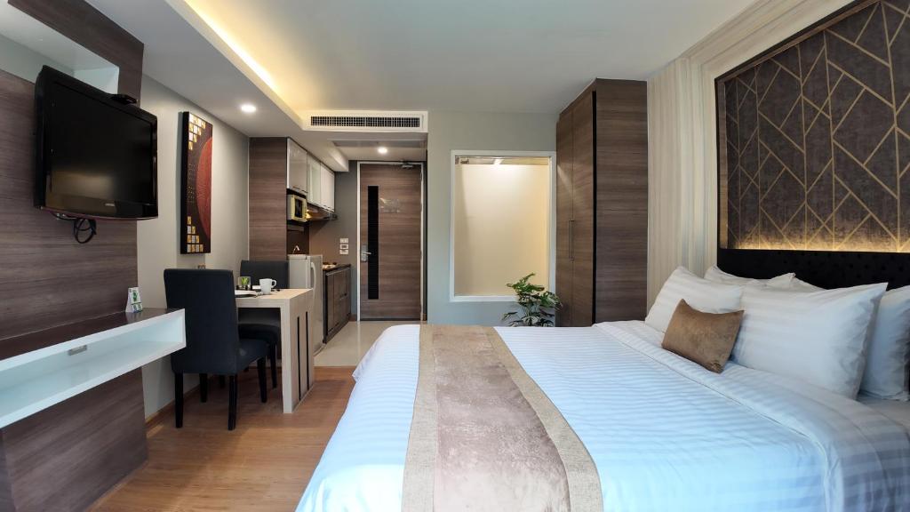 バンコクにあるAspira Suites Sukhumvit 20の大きなベッドとデスクが備わるホテルルームです。