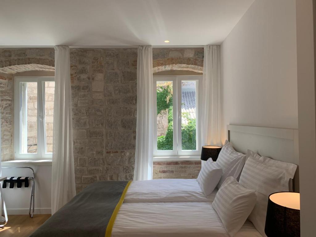 1 dormitorio con 1 cama grande y 2 ventanas en Priuli Luxury Rooms, en Split