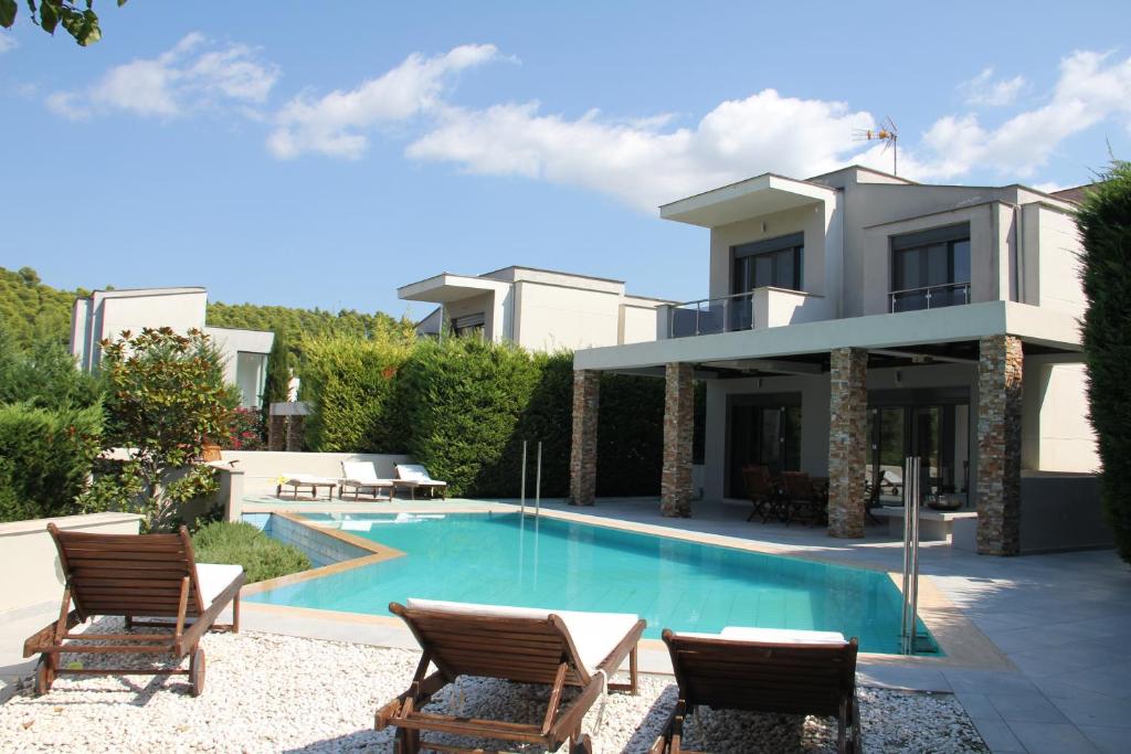 a villa with a swimming pool in front of a house at Serenity Villa in Sani in Sani Beach