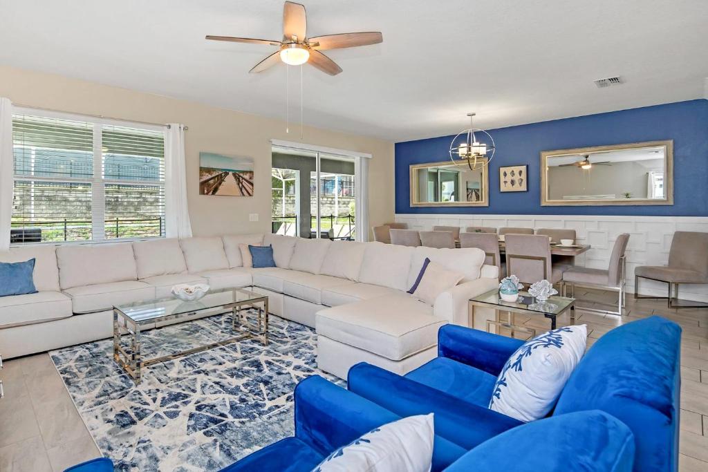sala de estar con sofá blanco y sillas azules en 8BR Luxury - Sleeps 22 - Near Disney with Pool & Hot Tub!, en Davenport