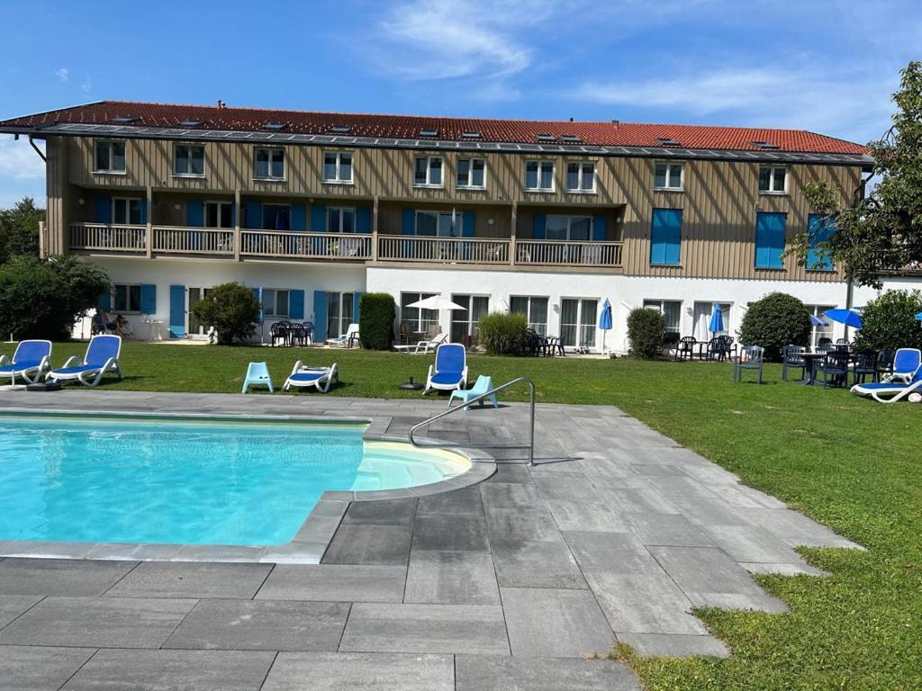 a large building with a swimming pool and chairs at Gabi mit Pool und Sauna in Übersee