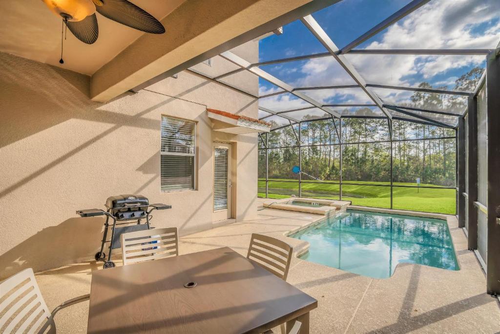 a patio with a pool and a table and chairs at Near Disney - 5BR Home- Games Pool Hot Tub & BBQ in Kissimmee