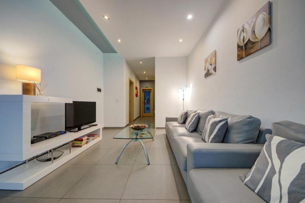 a living room with a couch and a television at Sliema 2 Bedroom close to seafront in Sliema