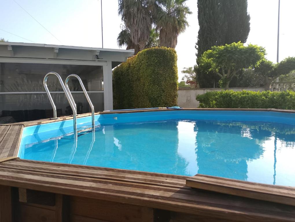 a blue swimming pool with a wooden deck at Casa Alba by My Home Apulia in Torre Lapillo