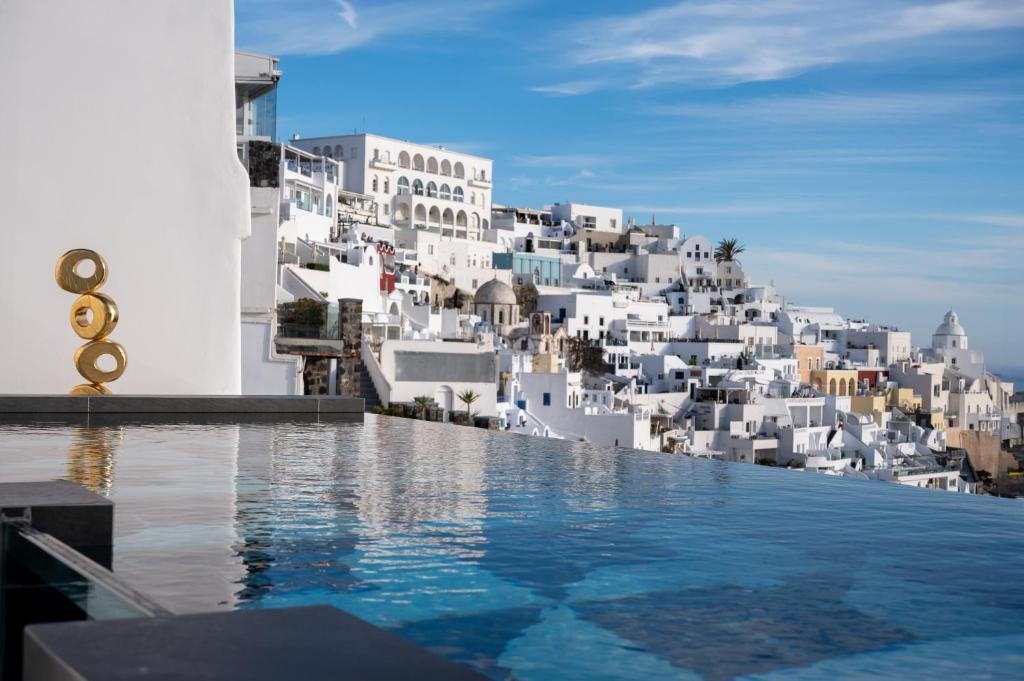a view from the infinity pool of a hotel with white buildings at CASA SUNSHA SANTORINI in Fira