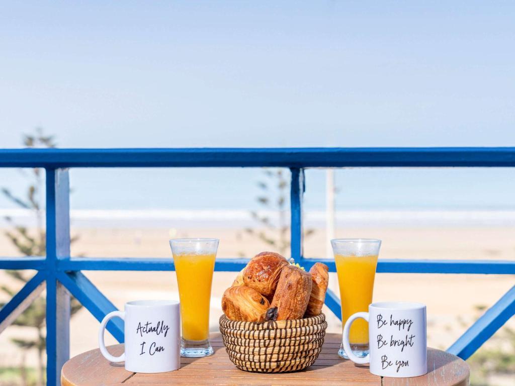 a basket of bread and two glasses of orange juice at Le Médina Essaouira Thalassa Sea & Spa - MGallery Collection in Essaouira
