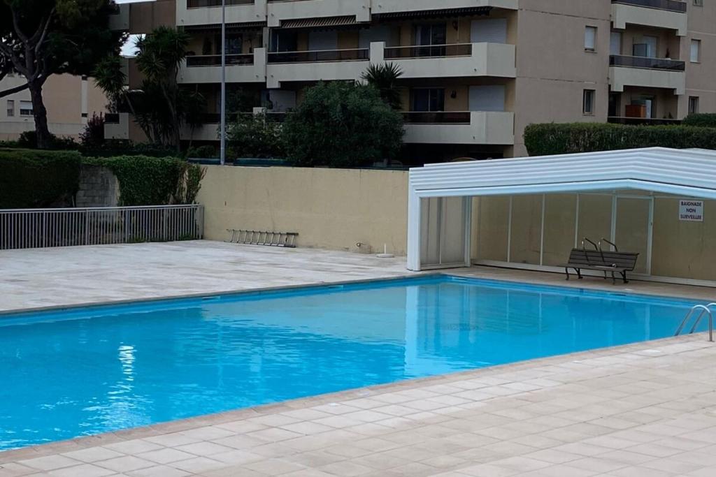 niebieski basen z pawilonem obok budynku w obiekcie 06U - Beautiful studio in residence - swimming pool and tennis court w mieście Saint-Laurent-du-Var