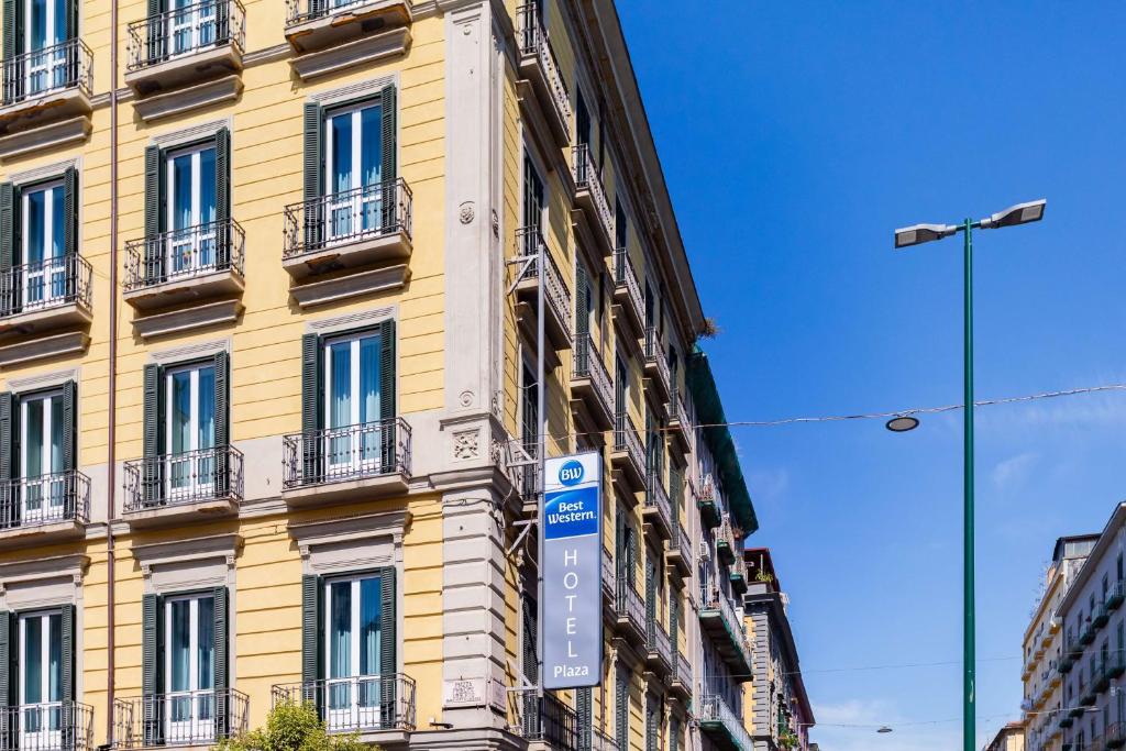 un edificio amarillo con un cartel delante en Best Western Hotel Plaza en Nápoles