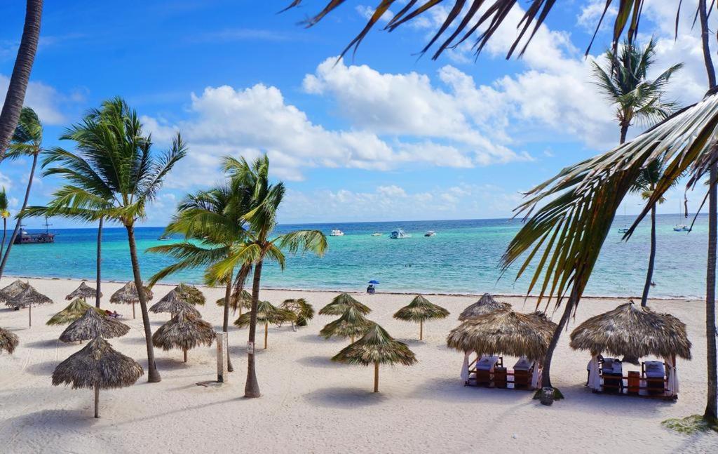 uma praia com muitos guarda-sóis de palha e o oceano em CORAL SUITES BEACH and SPA playa LOS CORALES em Punta Cana