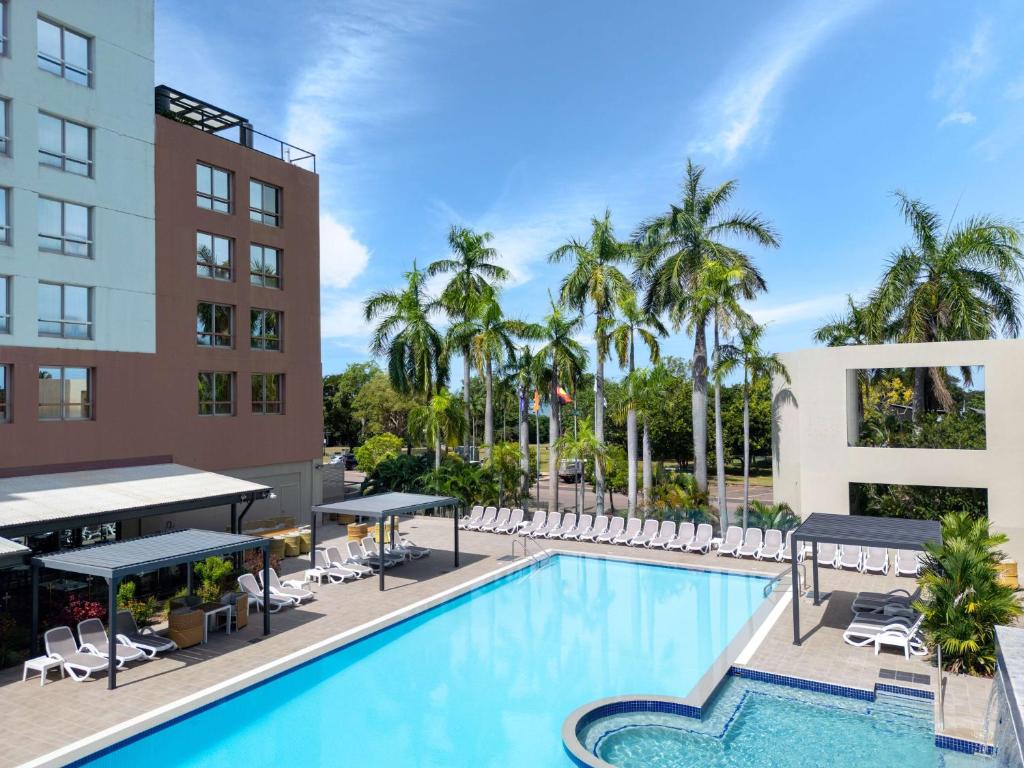 une image d'une piscine dans un hôtel avec des palmiers dans l'établissement DoubleTree by Hilton Esplanade Darwin, à Darwin