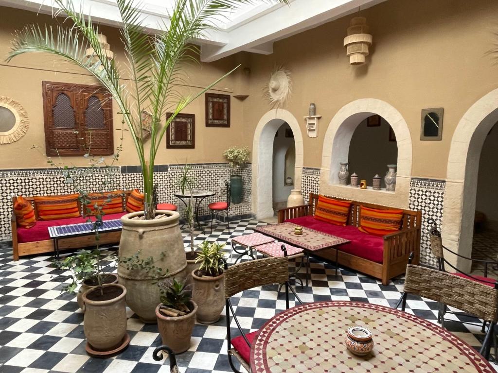 a living room with couches and tables and a palm tree at Riad Sidi Magdoul in Essaouira