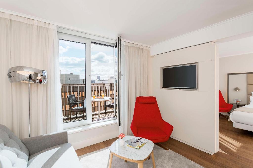 柏林的住宿－米特區查理檢查哨NH精選酒店，客厅设有红色椅子和大窗户