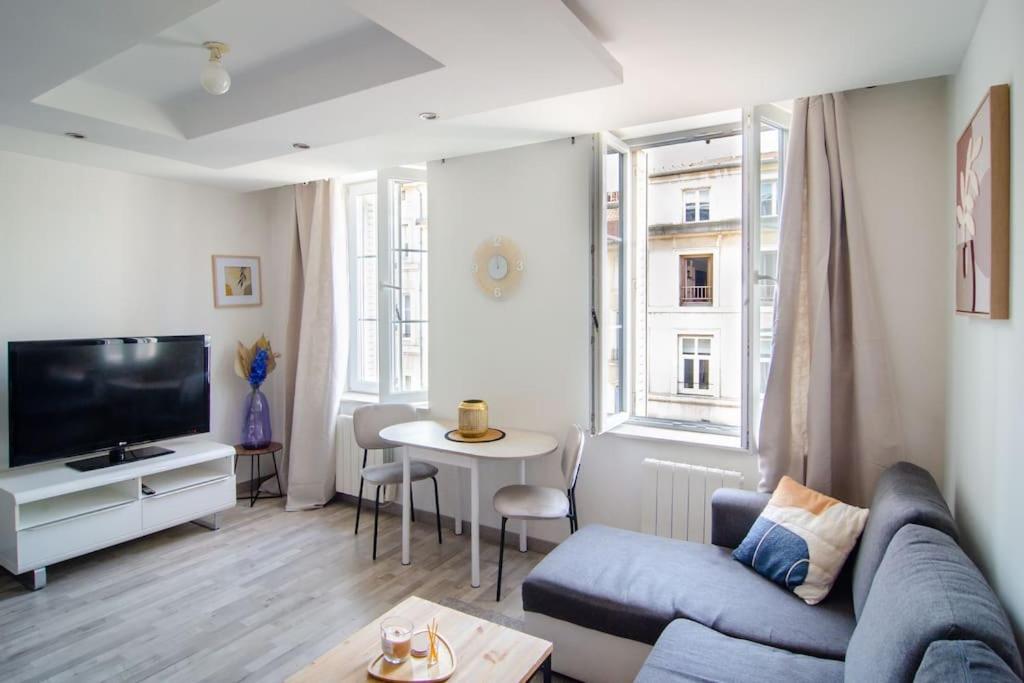 un salon avec un canapé, une télévision et une table dans l'établissement Charmant T2 à deux pas de la célèbre place Stanislas, à Nancy