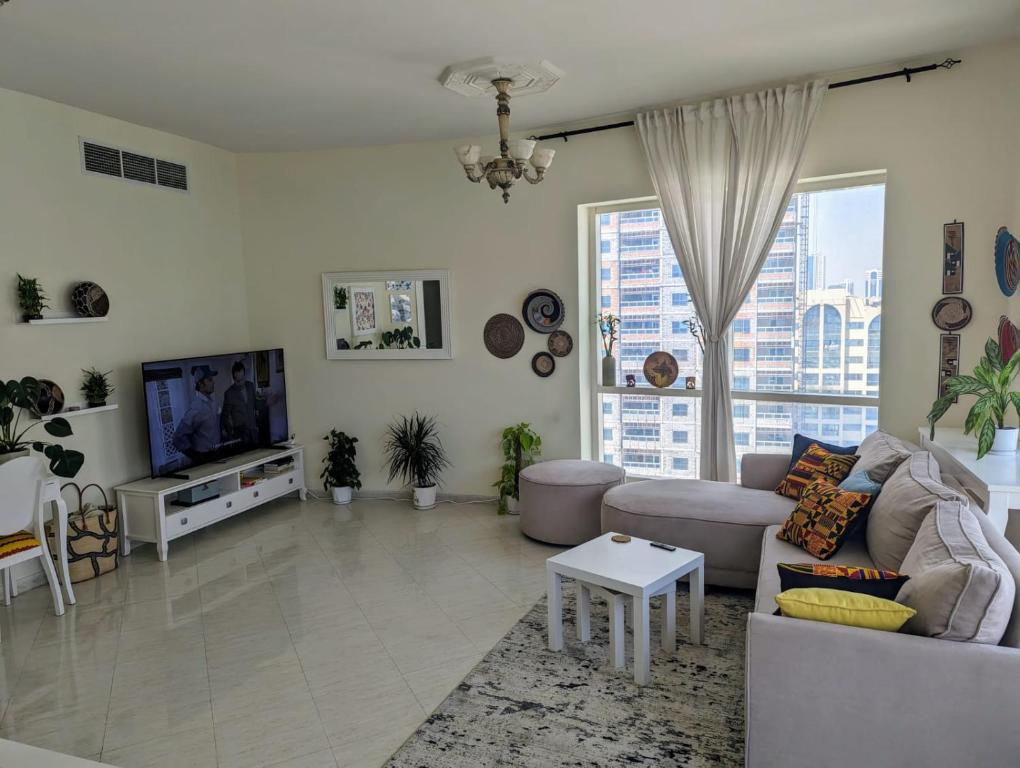 a living room with a couch and a tv at Home stay - FEMALE GUEST ONLY -ممنوع دخول الرجال in Sharjah
