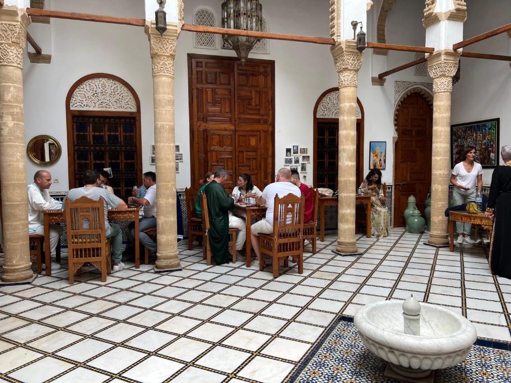 a group of people sitting at tables in a restaurant at Riad marco andaloz in Sale