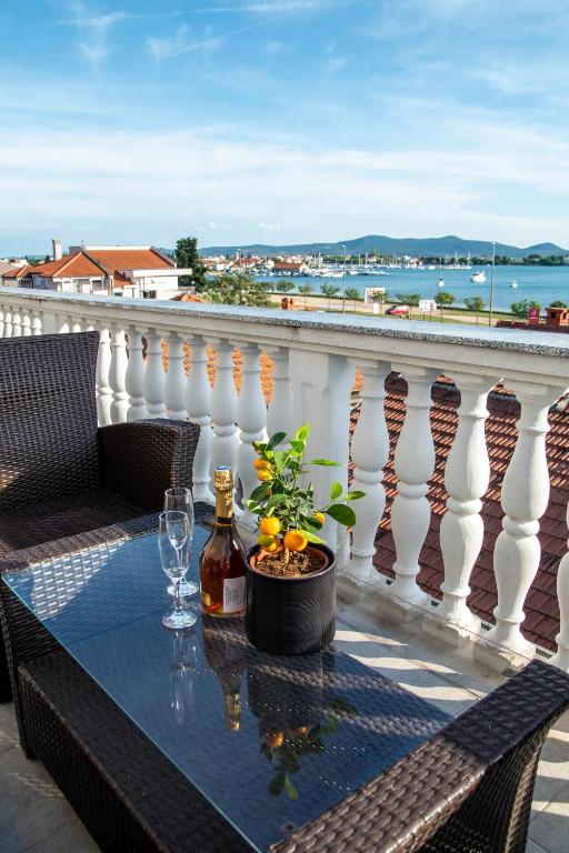 a table with a bottle of wine and a plant on a balcony at Guest House Maritimo in Sukošan