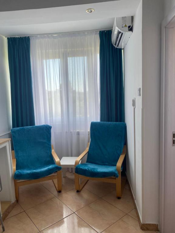 2 sillas azules en una habitación con ventana en Studio Garsoniera 552, en Bucarest