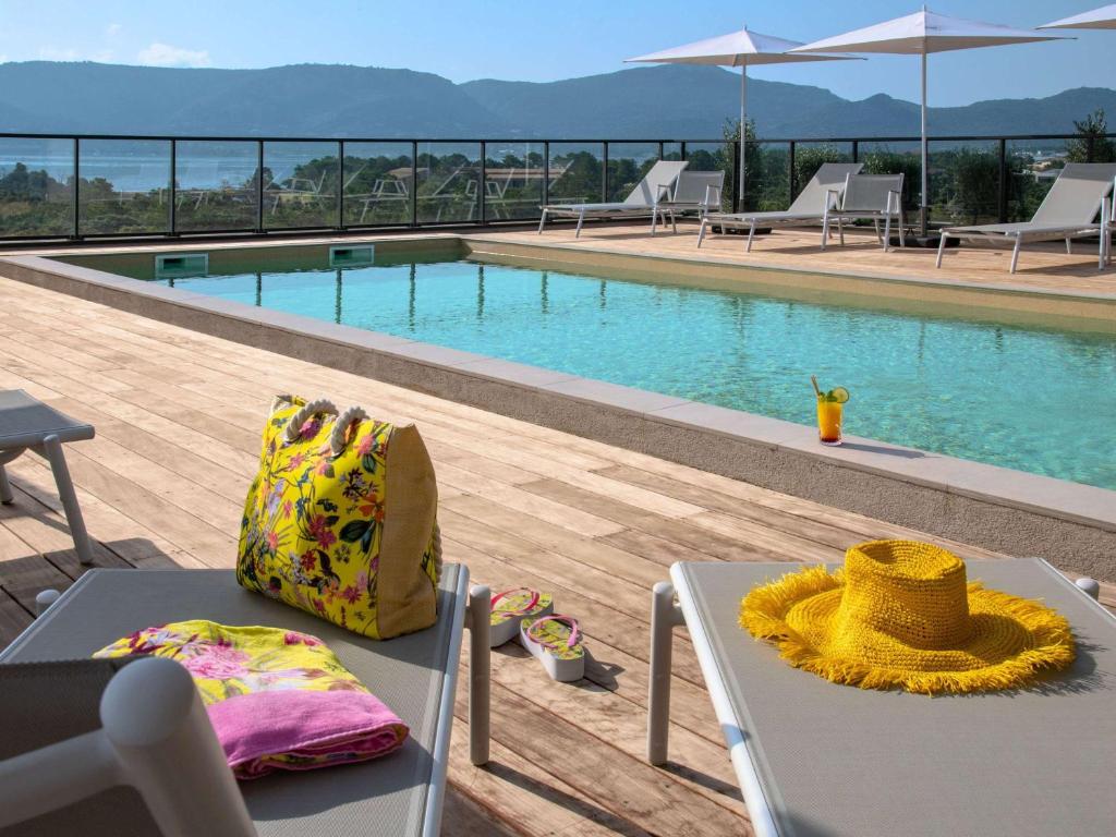 a view of a swimming pool with a table and chairs at ibis Styles Porto Vecchio in Porto-Vecchio