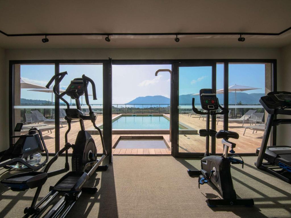 a gym with cardio machines and a view of a pool at ibis Styles Porto Vecchio in Porto-Vecchio