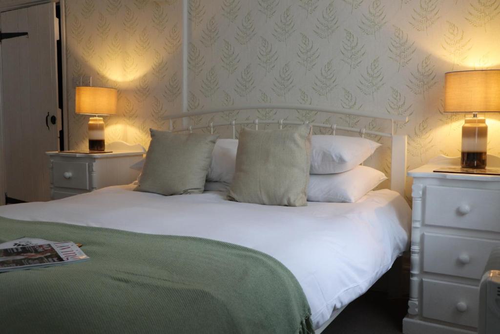 a bedroom with a white bed with pillows and two lamps at Chapter Two Bar in Malton