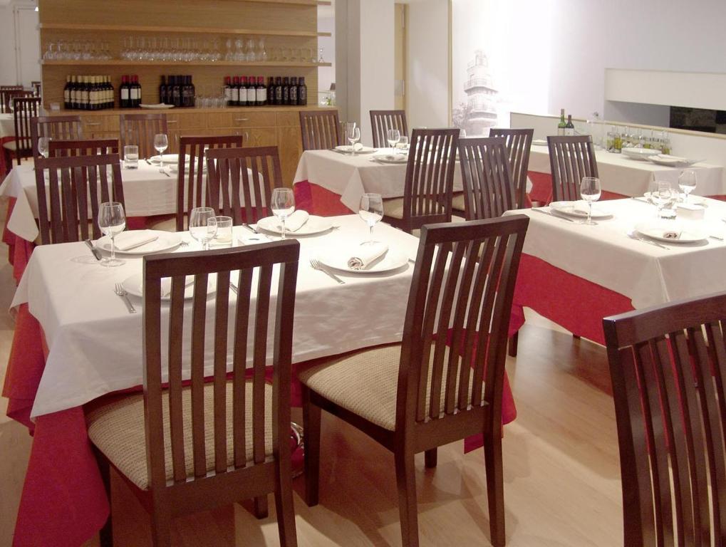 un comedor con mesas blancas y sillas con copas de vino en Gastro Hotel La Giraldilla, en Liérganes