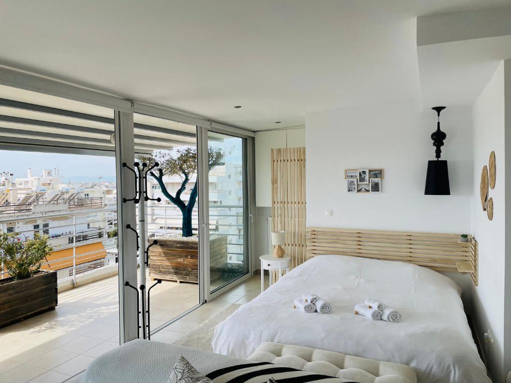 1 Schlafzimmer mit einem weißen Bett und einem Balkon in der Unterkunft Sea View Luxury Studio Palaio Faliro in Athen