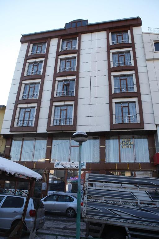 カルスにあるKars Center Hotelの前に車が駐車されている高い建物